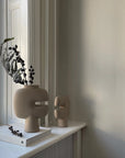 Decorative vase and sculpture on a shelf with a book and plant