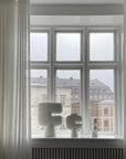 Decorative vases on a windowsill with a view of buildings outside
