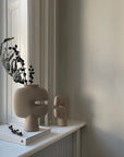 Two 101Cph Tribal Vase Mini Sand 221002s sit on a window sill next to a book from the Tribal Collection. Available at Spacio India