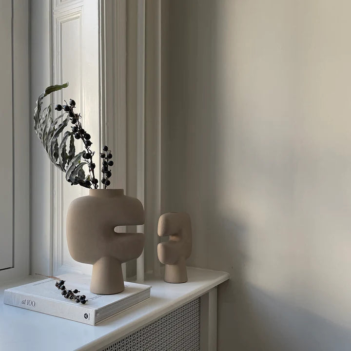 Two 101Cph Tribal Vase Mini Sand 221002s sit on a window sill next to a book from the Tribal Collection. Available at Spacio India