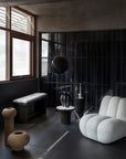 Modern interior with a white armchair, black bench, and decorative vases.