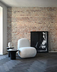 Modern interior with a textured brick wall, white armchair, and abstract painting.