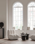 Modern living room with two white armchairs and calacatta marble top side tables in front of large windows.
