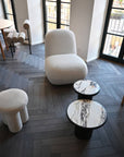 Modern interior with textured chairs and marble tables on a wooden floor.