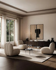 Modern living room with beige chairs, a coffee table, and a large mirror on the wall.