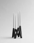 Modern black candle holder with three white candles on a gray background from 101 Copenhagen at Spacio retail stores in Mumbai & Kolkata.