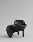 Black ceramic bowl on a gray background from 101 Copenhagen at Spacio retail stores in Mumbai & Kolkata.