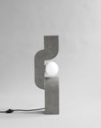 Modern concrete table lamp with a white bulb on a gray background from 101 Copenhagen at Spacio retail stores in Mumbai & Kolkata.