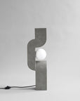 Modern concrete table lamp with a white bulb on a gray background from 101 Copenhagen at Spacio retail stores in Mumbai & Kolkata.