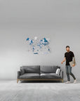 Man standing next to a gray sofa with a world map wall decoration in a minimalistic room.