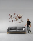 Man standing next to a gray sofa with a large size world map wall decoration in a minimalistic room.