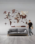 Man standing next to a 2XL world map wall decoration in a room with a gray sofa.
