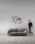 Man standing next to a gray sofa with a medium size decorative wall map in a minimalistic room.