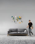 Man standing next to a gray sofa with a colorful world map on the wall.