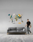 Man standing next to a gray sofa with a colorful world map on the wall in a modern living room.