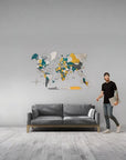 Man standing next to a gray sofa with a colorful world map on the wall in a modern living room.