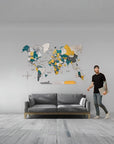 Man standing next to a world map wall decoration in a living room.