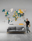 Man standing next to a world map wall decoration in a living room.