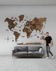 Man standing next to a 3XL size world map wall decoration in a room with a gray sofa.