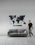 Man standing next to a world map wall decal in a living room.