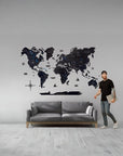 Man standing next to a large world map wall decal in a living room.