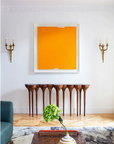 In this living room, a beautifully crafted Agrippa Esgrimas Console by Agrippa stands against the wall, elegantly complementing the space with its simple shapes. A stunning orange painting hangs above, adding a naturalistic touch.