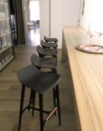 European luxury bar stools, like the Agrippa Morgan Bar Stool or Agrippa Spain, line a sleek black row in a luxurious bar.