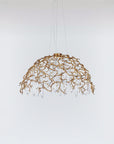 A dome shaped chandelier hanging on wires with water drops shaped glass suspended from branches in gold colour