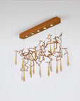 A ceiling chandelier with water droplets in gold colour glass hanging on gold colour branches.