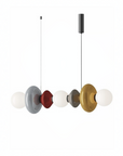 A modern multi-light linear pendant chandelier with five translucent glass globes and circular metal shades in white, gray, red, dark gray, and gold, suspended against a plain white background.