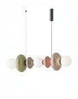 A modern multi-light linear pendant chandelier with five translucent glass disc shades in muted olive green, taupe, dusty rose, and beige, each paired with a white spherical bulb, suspended against a solid white background.