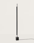 A tall modern design floor lamp on a light grey colour background.