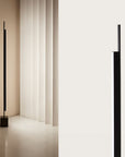 A tall modern design floor lamp in a corner of a living room.