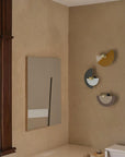 4 Wall lights in different colours discs in different colours in the corner of a room on a beige colour wall.