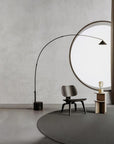 A modern design floor lamp in marble and metal in front of a large round window and chair in a grey beige theme room.