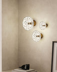 A set of three crystal wall lamps in a warm corner of a living room styled with decorative elements.