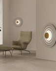 A living room corner with a round disc wall lights and green plant.