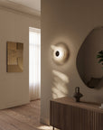 A modern and warm these entrance foyer with a wall art, credenza, mirror, wall lamp and decorative art object.