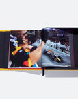 Open book showing a racing car on a track with a person in a racing suit.