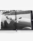 Open book showing a black and white photograph of a person in a vintage car.