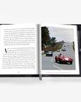 Open book with a photograph of vintage cars on a road