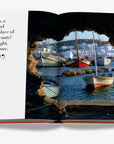 Artistic photograph of boats at Paros harbour paired with a captivating quote in Assouline's Greek Islands luxury book, available at Spacio India.