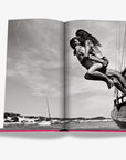 Romantic monochrome image of couple leaping from yacht in Assouline Ibiza Bohemia Coffee Table Book, luxury travel edition at Spacio India.