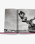 Romantic monochrome image of couple leaping from yacht in Assouline Ibiza Bohemia Coffee Table Book, luxury travel edition at Spacio India.