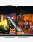 A breathtaking aerial view of the Las Vegas Strip at night, featuring the Bellagio Fountains and dazzling neon lights, from Las Vegas Magic by Assouline, available at Spacio India.