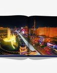 A breathtaking aerial view of the Las Vegas Strip at night, featuring the Bellagio Fountains and dazzling neon lights, from Las Vegas Magic by Assouline, available at Spacio India.