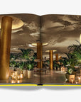 A sophisticated Miami hotel lobby adorned with lush indoor greenery, golden accents, and ambient lighting. Captured in the Assouline Coffee Table Book Miami Beach, available at Spacio India.