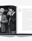 Black-and-white photograph from Assouline’s Luxury Jewellery Watch Coffee Table Book depicting Albert and Joshua Ganjei, founders of European Watch Company, examining fine watches.