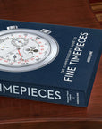 Assouline's Fine Timepieces Luxury Watch Coffee Table Book placed on an elegant wooden table, showcasing the sophisticated blue cover and Patek Philippe watch face, available at Spacio India.