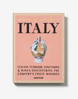 On a white background. A luxurious hardbound Assouline coffee table book, Wine & Travel Italy, featuring Italy’s top vineyards, fine wines, and the art of winemaking.